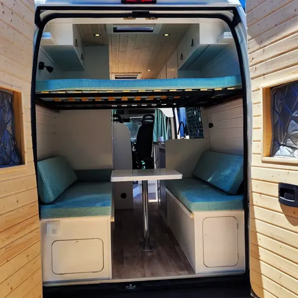 Camper con cama elevable sobre la dinette y asientos tapizados