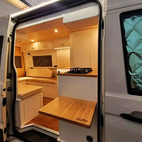 Camper vista desde la puerta lateral con dinette, mesa y cocina