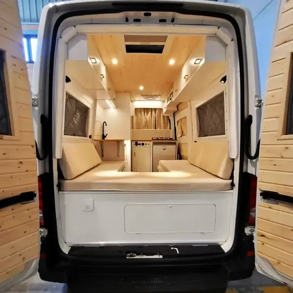 Camper abierta por las puertas traseras con la cama y el interior iluminado