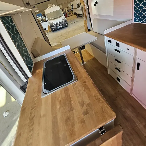 Cocina de camper con encimera de madera y placa vitrocerámica