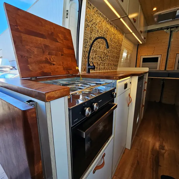 Cocina de camper con horno y encimera de madera oscura