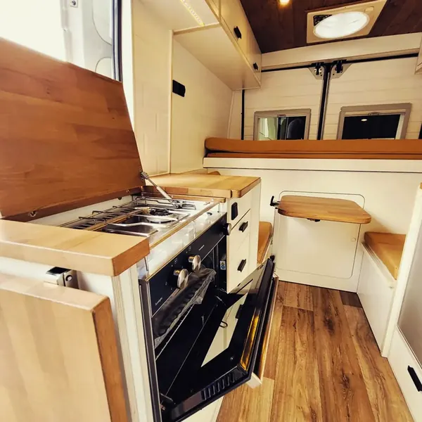 Cocina de camper con horno, encimera de madera y suelo de madera