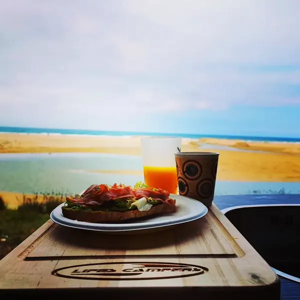 Desayuno sobre la tabla de cortar de una camper con vistas al mar