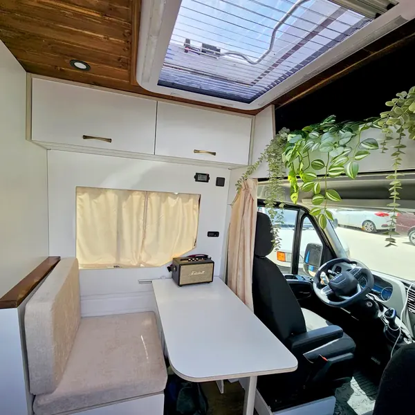 Salón con mesa junto a la cabina en una Iveco Daily camperizada